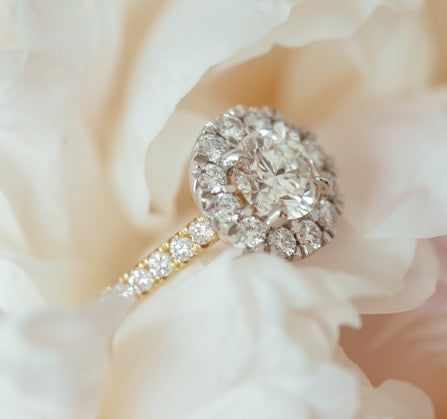 Makrofotografering av en diamantring placerad på vita blomblad.