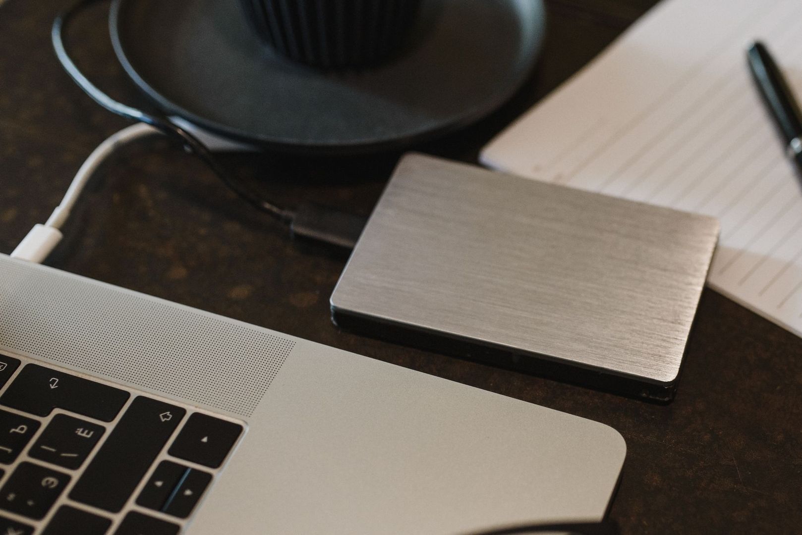 Bärbar dator och extern hårddisk med kabel på ett skrivbord