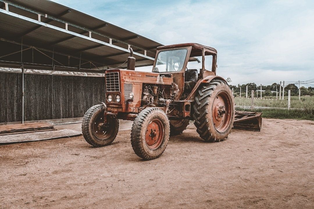 Äldre röd traktor fotograferad framför en öppen lantbruksbyggnad